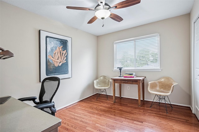 home office with light wood-type flooring, a ceiling fan, and baseboards