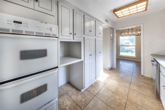 911 Prestwick Ln, Richardson, TX 75080 - kitchen with an inviting chandelier, white double oven, light tile patterned floors, light countertops, and visible vents