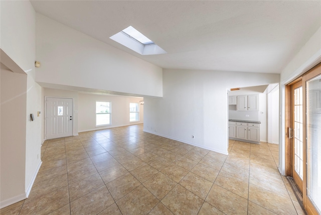 911 Prestwick Ln, Richardson, TX 75080 - unfurnished living room with light tile patterned floors, baseboards, high vaulted ceiling, and a skylight