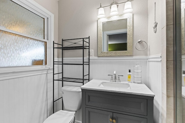 1701 W Birge St, Sherman, TX 75092 - full bath featuring a wainscoted wall, vanity, toilet, a shower with shower door, and a textured wall
