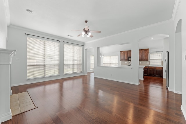 1716 Yarmouth Ln, Mansfield, TX 76063 - unfurnished living room with dark wood-type flooring, arched walkways, ceiling fan, and crown molding