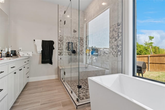 full bath featuring a freestanding tub, vanity, plenty of natural light, and a stall shower
