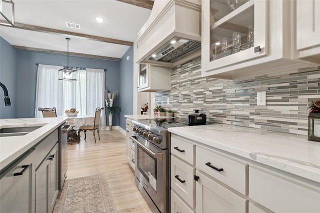 kitchen featuring a sink, visible vents, stainless steel appliances, premium range hood, and light wood-type flooring