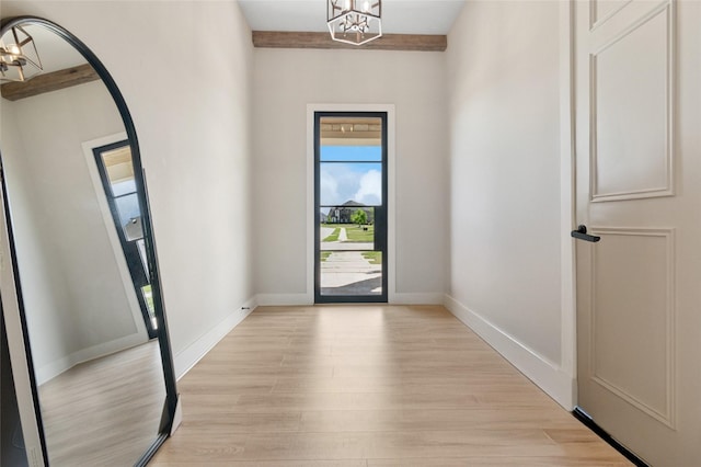doorway featuring an inviting chandelier, light wood-style flooring, and baseboards