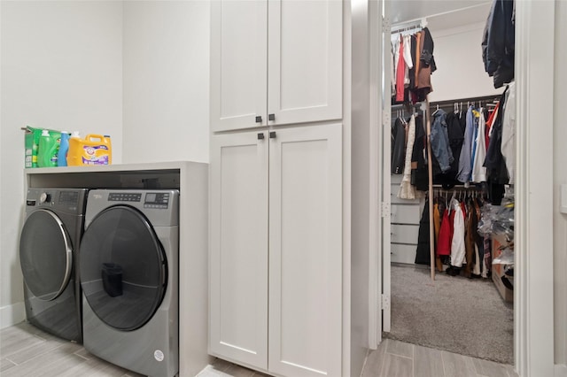 washroom featuring wood finish floors, cabinet space, and independent washer and dryer