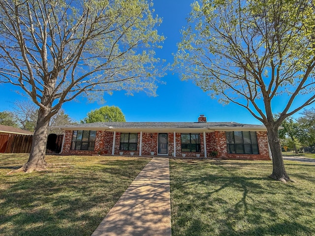 ranch-style house featuring a chimney, a front yard, and brick siding