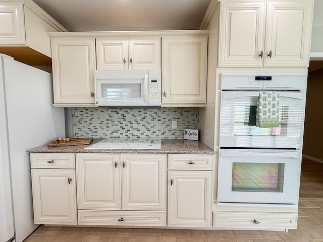 kitchen with light stone counters, light tile patterned flooring, white appliances, and backsplash