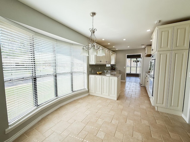 kitchen with tasteful backsplash, recessed lighting, decorative light fixtures, stone finish floor, and baseboards