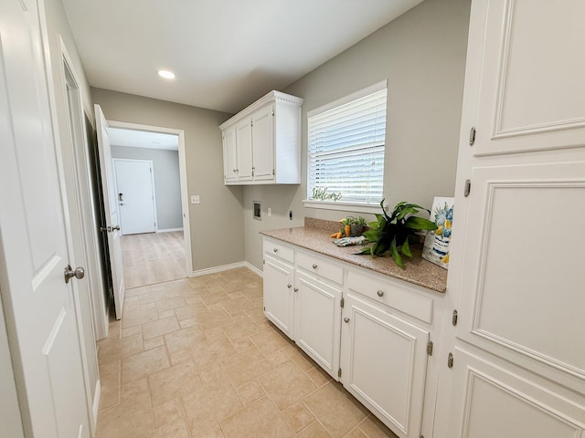 laundry room with hookup for an electric dryer, cabinet space, washer hookup, stone finish flooring, and baseboards