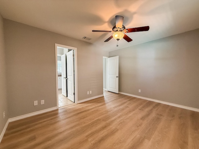 unfurnished bedroom featuring visible vents, light wood-type flooring, ensuite bathroom, and baseboards