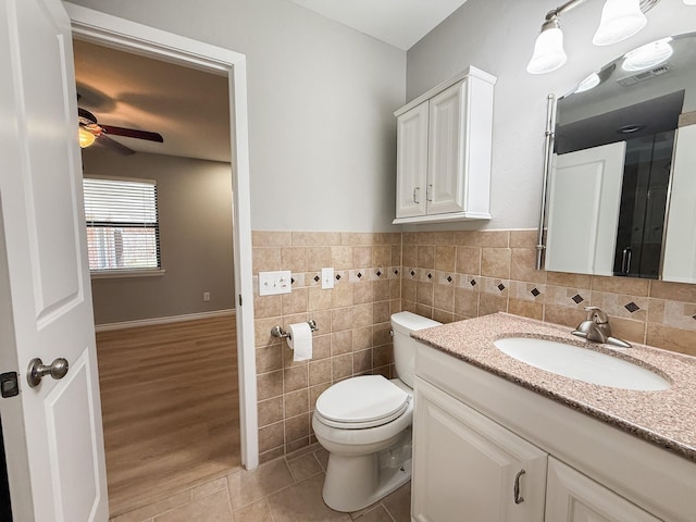 bathroom with tile patterned flooring, tile walls, ceiling fan, toilet, and vanity