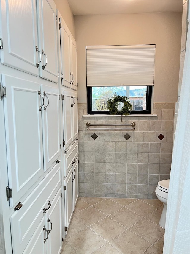 bathroom featuring toilet, tile walls, wainscoting, and tile patterned floors