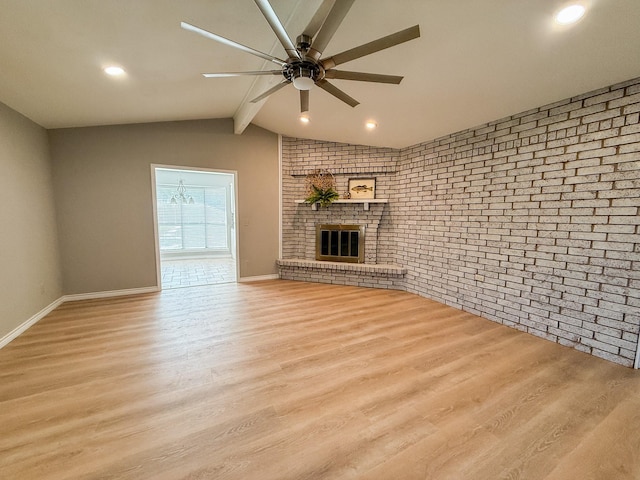 unfurnished living room with wood finished floors, lofted ceiling with beams, brick wall, a brick fireplace, and a ceiling fan