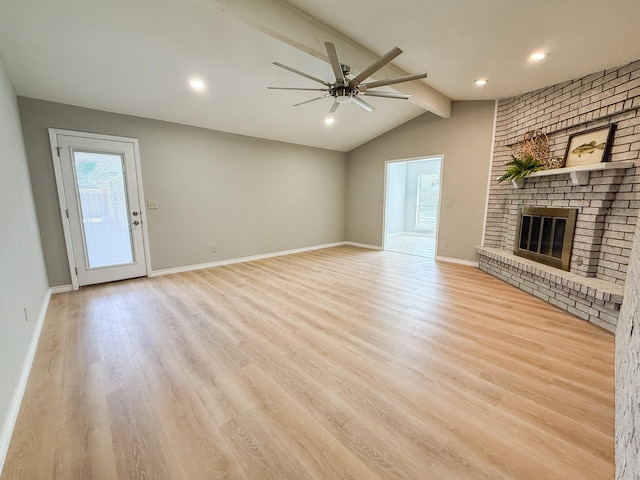 unfurnished living room with light wood finished floors, a brick fireplace, ceiling fan, vaulted ceiling with beams, and baseboards