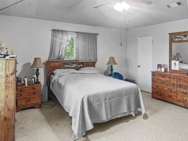 carpeted bedroom featuring a ceiling fan and visible vents