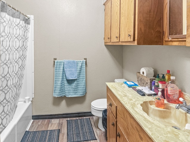 full bath featuring shower / bath combo, wood finished floors, vanity, baseboards, and toilet