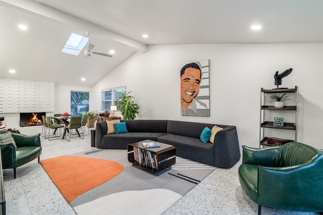 living area featuring beam ceiling, recessed lighting, a skylight, and a fireplace