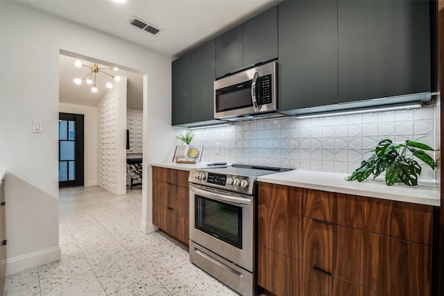 kitchen featuring decorative backsplash, appliances with stainless steel finishes, visible vents, light countertops, and baseboards