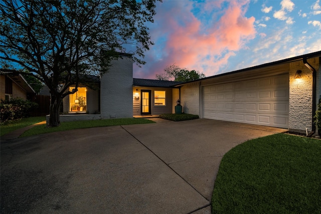 view of front facade featuring driveway, a chimney, a lawn, and a garage
