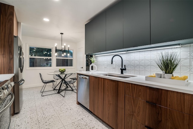kitchen with tasteful backsplash, appliances with stainless steel finishes, a sink, baseboards, and modern cabinets