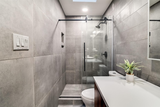 bathroom featuring vanity, toilet, a shower stall, and tile walls