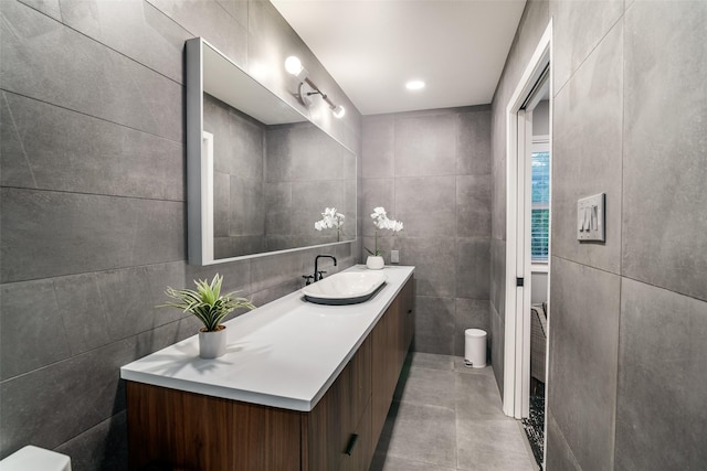 bathroom with toilet, vanity, tile walls, and tile patterned floors