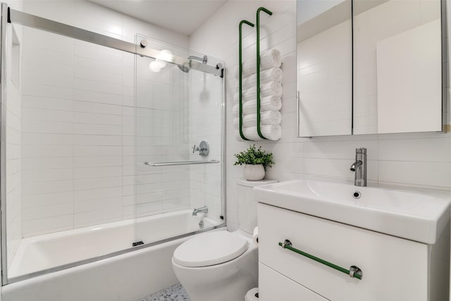 full bathroom with combined bath / shower with glass door, toilet, tile walls, vanity, and backsplash