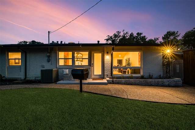 rear view of property featuring a lawn, fence, and central AC unit