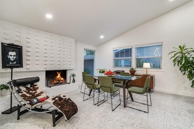 dining room featuring baseboards, recessed lighting, a stone fireplace, and lofted ceiling