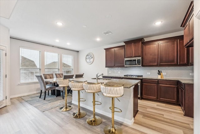2203 Lannister St, Mansfield, TX 76063 - kitchen featuring visible vents, light wood-style floors, a breakfast bar area, a sink, and appliances with stainless steel finishes