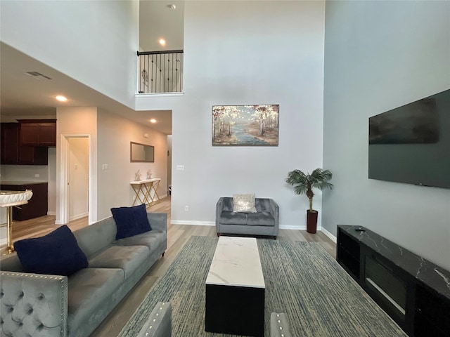 living room with light wood-style flooring, recessed lighting, baseboards, a towering ceiling, and visible vents