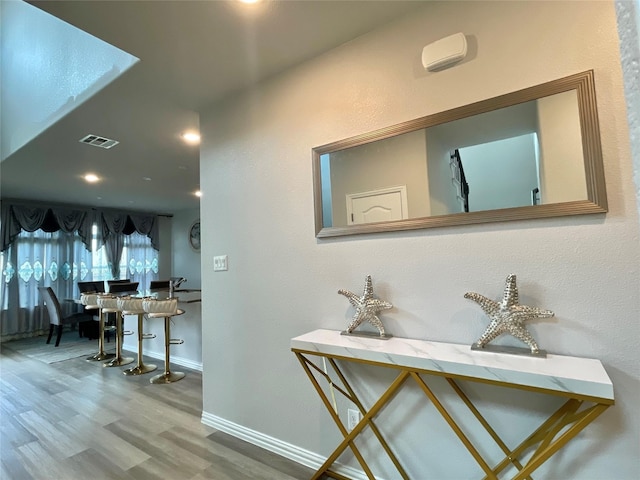 hall with baseboards, recessed lighting, wood finished floors, and visible vents