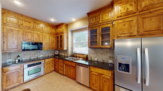 kitchen featuring a sink, tasteful backsplash, brown cabinets, light tile patterned flooring, and black appliances