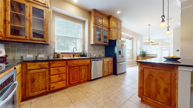 kitchen with appliances with stainless steel finishes, brown cabinets, light tile patterned floors, and a sink