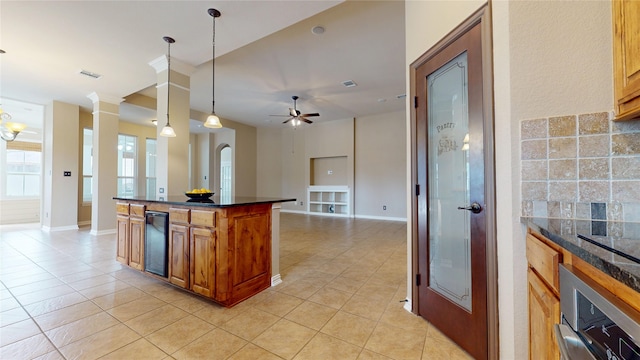 kitchen featuring wall oven, light tile patterned floors, brown cabinetry, ceiling fan, and visible vents