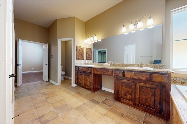bathroom featuring toilet, double vanity, a sink, and a washtub
