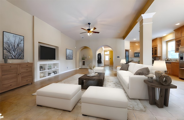 living area with light tile patterned floors, built in features, a ceiling fan, and arched walkways
