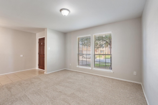 spare room with baseboards, light tile patterned floors, and light carpet