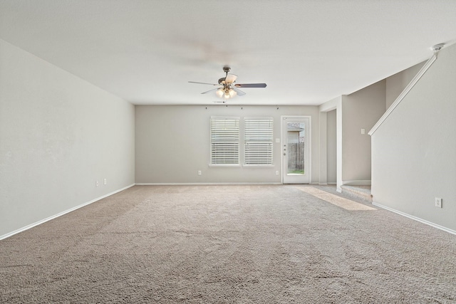 unfurnished living room with carpet flooring, ceiling fan, and baseboards