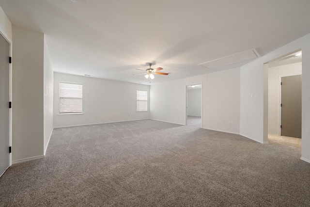 unfurnished room with baseboards, attic access, ceiling fan, and carpet