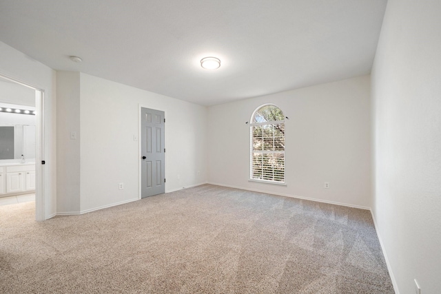 spare room with a sink, baseboards, and light carpet