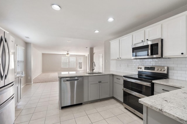 kitchen with stainless steel appliances, a wealth of natural light, a peninsula, and a sink