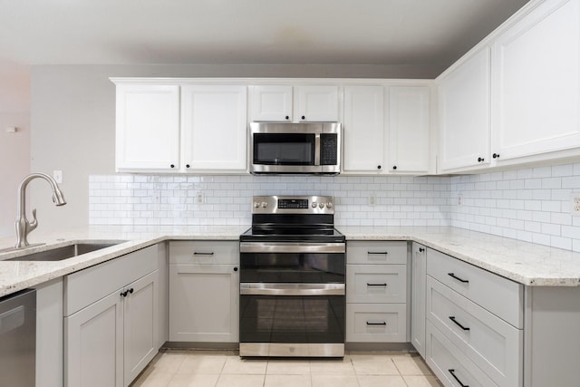 kitchen with white cabinets, light stone counters, appliances with stainless steel finishes, and a sink