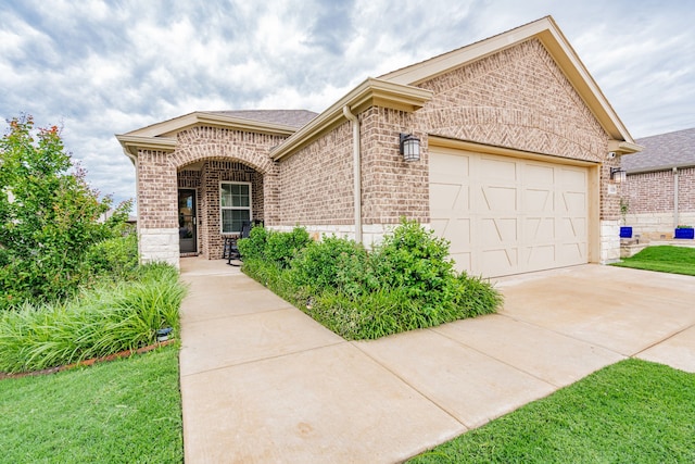 view of front of home featuring driveway, roof with shingles, an attached garage, and brick siding