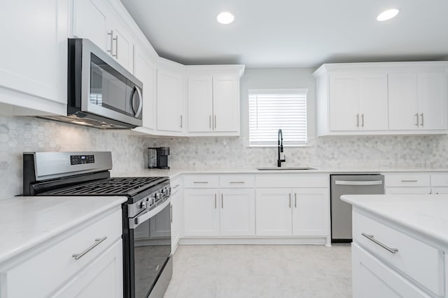 kitchen featuring backsplash, a sink, white cabinetry, and stainless steel appliances