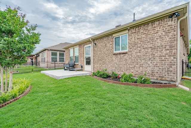 rear view of house featuring brick siding, fence, a yard, and a patio area
