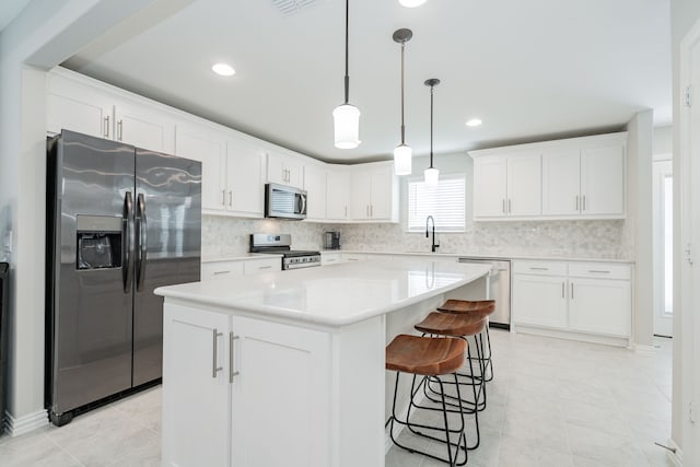 kitchen featuring stainless steel appliances, tasteful backsplash, a center island, light countertops, and white cabinets