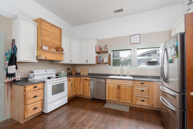kitchen with a sink, dark wood-style flooring, stainless steel appliances, visible vents, and dark countertops