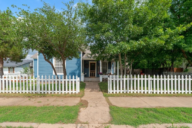view of property hidden behind natural elements featuring a fenced front yard and covered porch