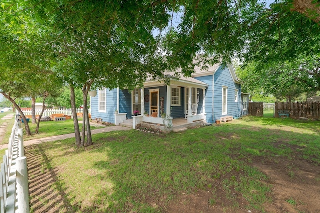 view of front of property with covered porch, a front lawn, and a fenced backyard
